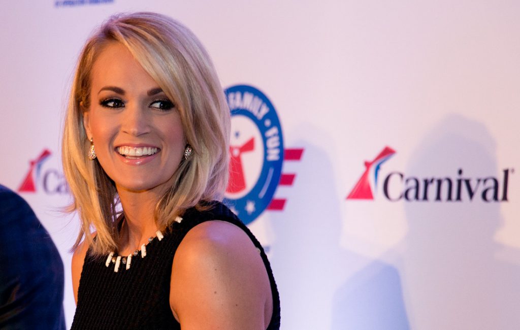 Carrie Underwood, right, reacts to a comment at a news conference Thursday, Jan. 28, 2016, in Jacksonville, Fla. At left is Brig. Gen. John Pray, president and CEO of Operation Homefront. Underwood, Operation Homefront and Carnival Cruise Line announced a partnership to begin a new initiative to support U.S. military families. The effort between the three entities is to raise funds through a series of projects during Underwood's concert tour and aboard Carnival's ships as well as the company's website. FOR EDITORIAL USE ONLY (Andy Newman/Carnival Cruise Line/HO)